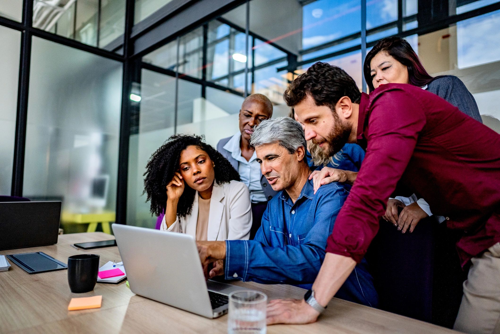 IT professionals collaborating around a laptop in a modern office